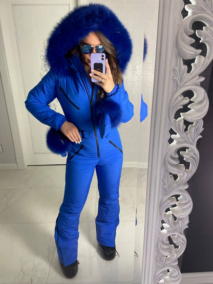 Person wearing a blue snowsuit with a fur-lined hood in front of a mirror.