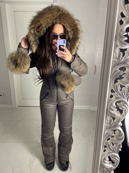 Person wearing a fur-lined hooded jacket and snow pants in front of a mirror.