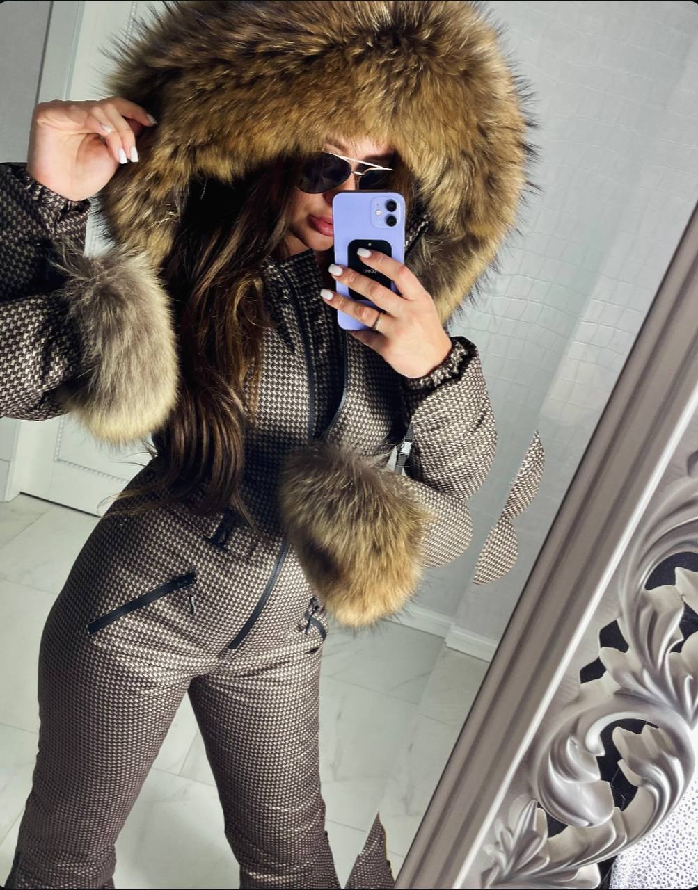 Person wearing a fur-lined coat taking a mirror selfie.