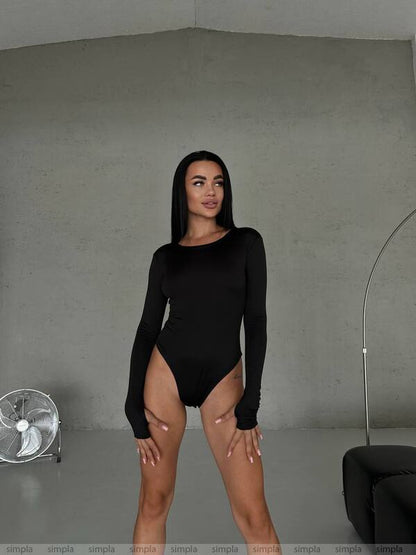 Woman wearing a black long-sleeve bodysuit against a gray background