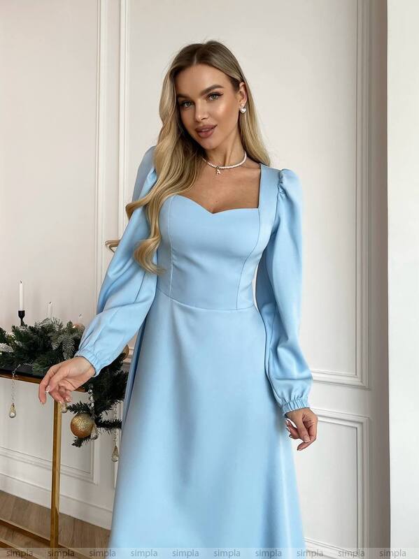 Woman wearing a light blue dress with long sleeves in an indoor setting.