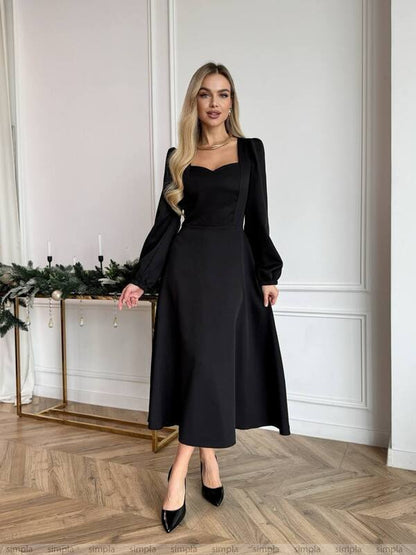 Woman in a black dress standing in a room with decorative elements.