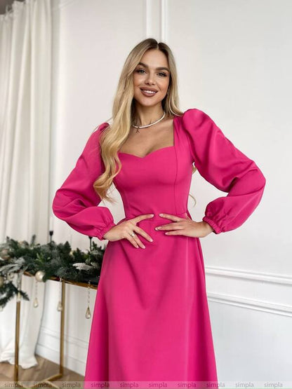 Woman wearing a bright pink dress with long sleeves in an indoor setting.
