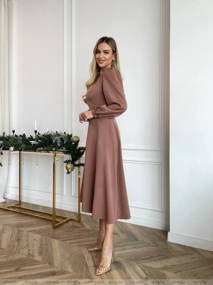 Woman in a pink dress standing in a stylish room with decorative elements.
