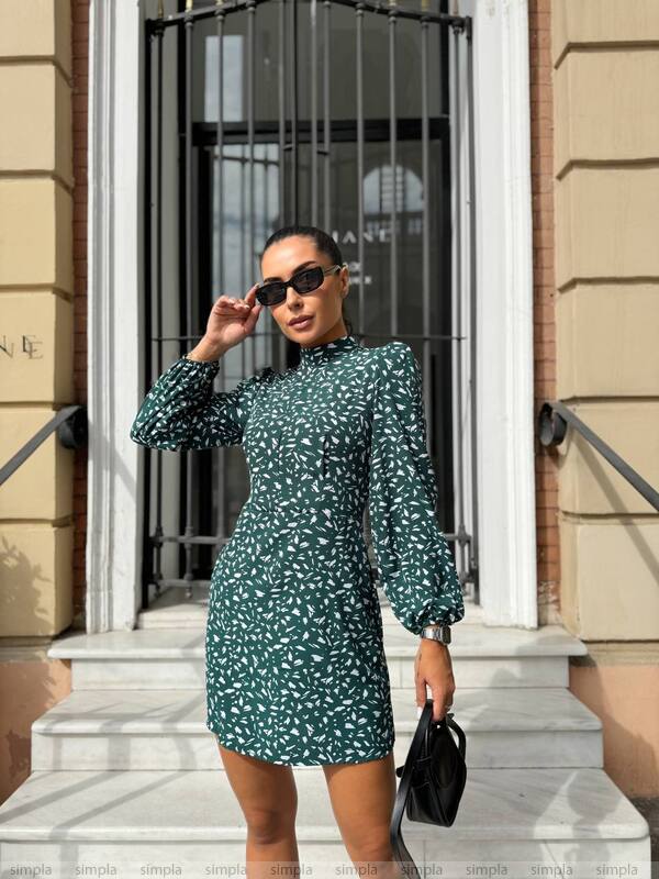 Woman in a green floral dress standing outside a building