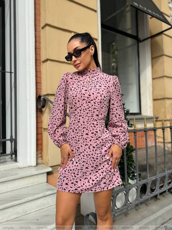 Woman wearing a pink patterned dress standing on a city street.