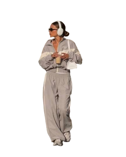 Person wearing a gray tracksuit with white stripes on a white background