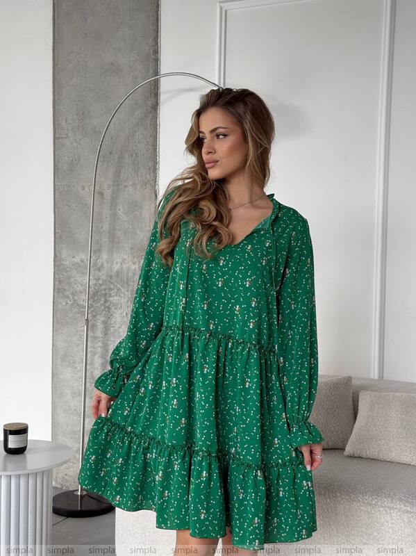 Woman wearing a green floral dress in a modern interior setting