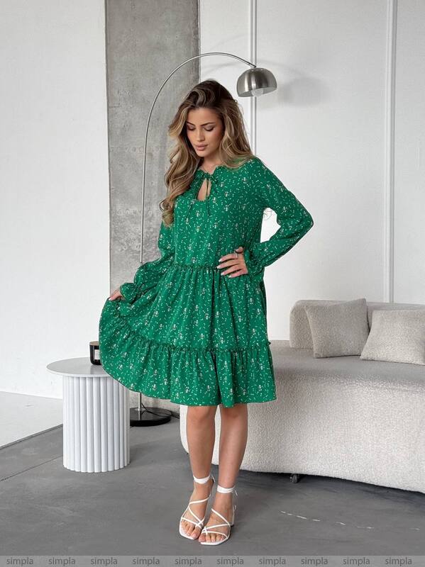 Woman wearing a green dress with a pattern in a modern living room.