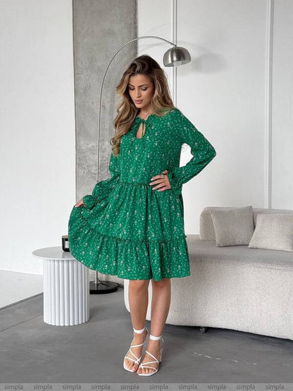 Woman wearing a green dress with a pattern in a modern living room.