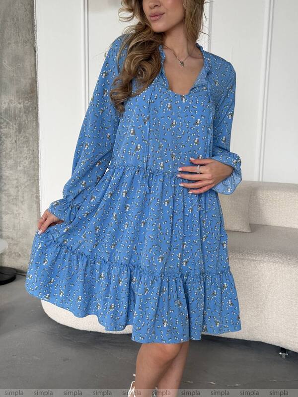 Woman wearing a blue floral dress in an indoor setting