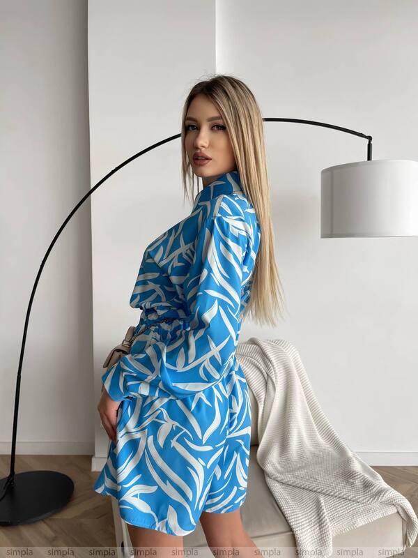 Woman wearing a blue and white patterned dress in a modern interior setting.