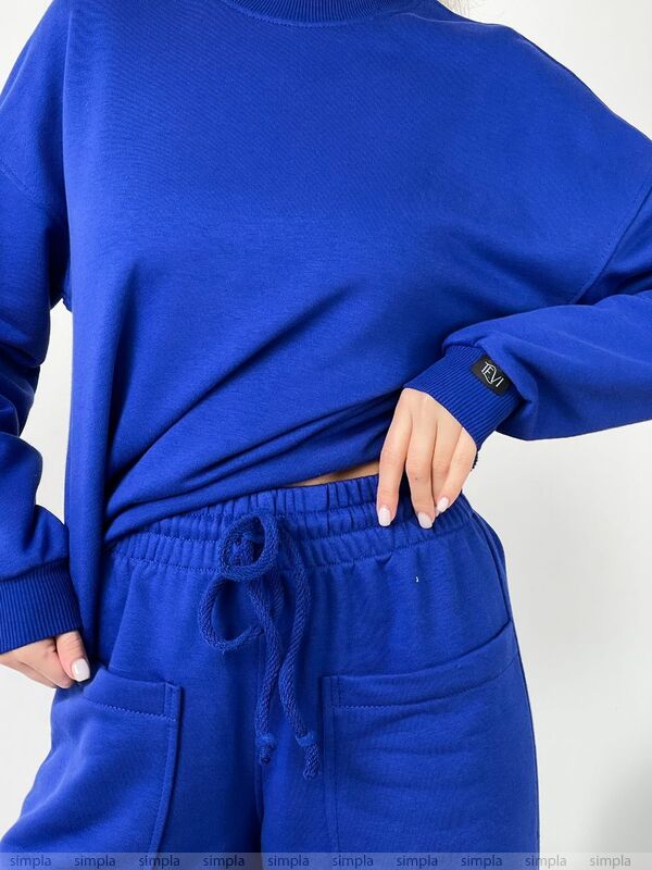 Person wearing a blue sweatshirt and matching pants on a white background
