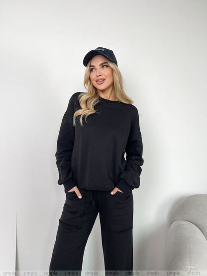Woman wearing a black outfit with a cap against a white background
