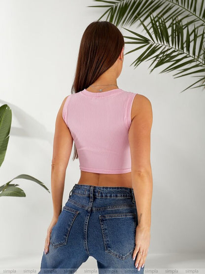 Person wearing a pink crop top and blue jeans with a white background and green leaves.