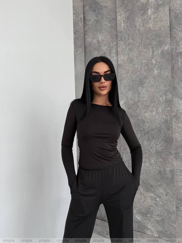 Woman wearing a black outfit against a gray wall