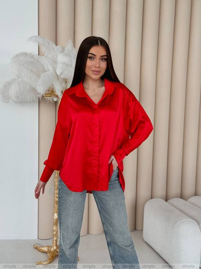 Woman wearing a red shirt and blue jeans standing in a room with decorative elements.