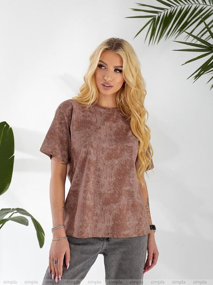 Woman wearing a brown t-shirt and gray pants against a white background with green leaves.