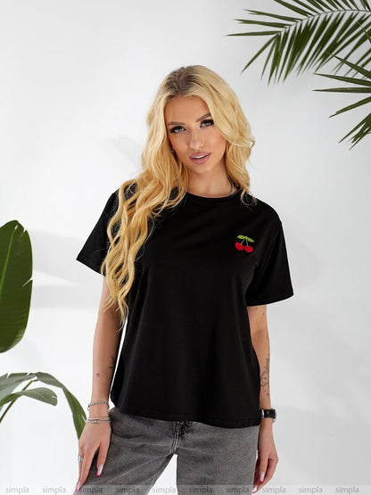 Woman wearing a black t-shirt with a cherry design against a white background with green leaves.