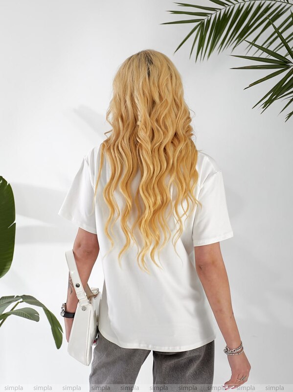 Person wearing a white t-shirt with a plant in the background