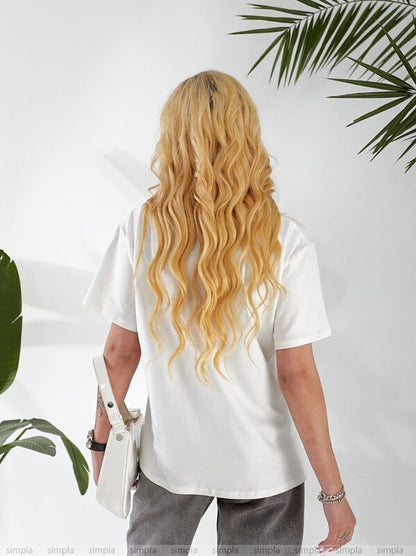Person wearing a white t-shirt with a plant in the background