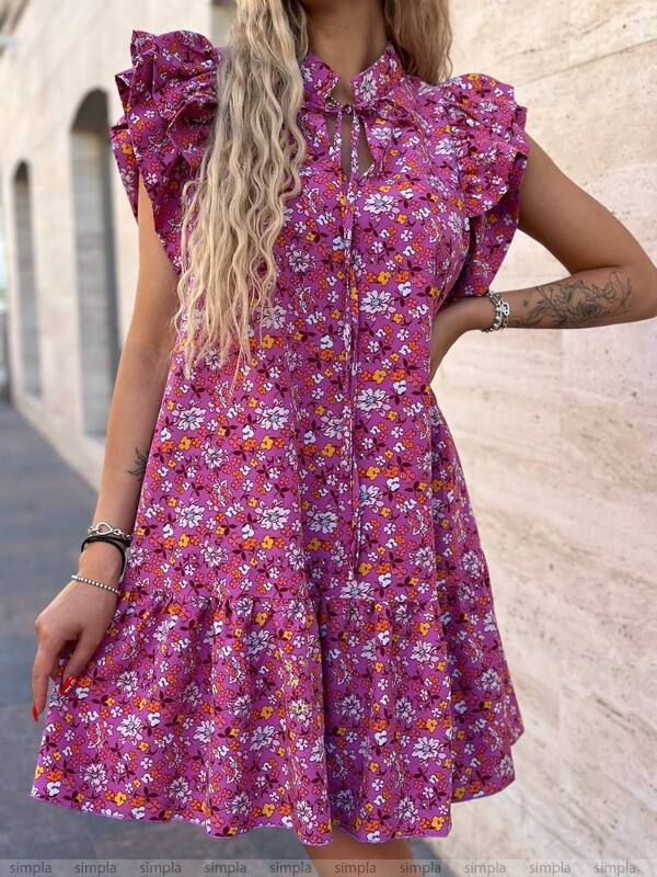 Woman wearing a pink floral dress with ruffled sleeves against a beige wall.