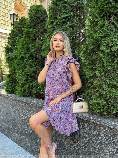 Woman in a floral dress standing outdoors with greenery in the background