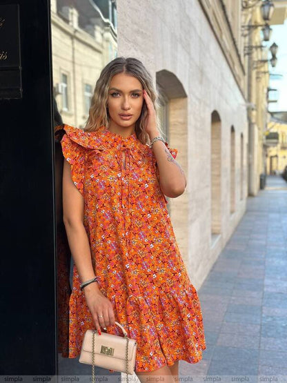 Woman in an orange floral dress standing on a street