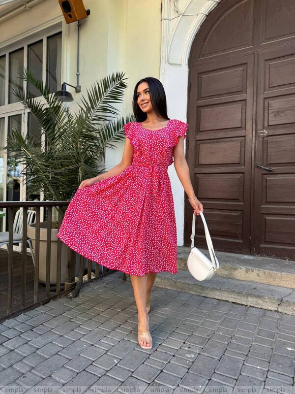 Woman in a pink dress walking outdoors near a building entrance.