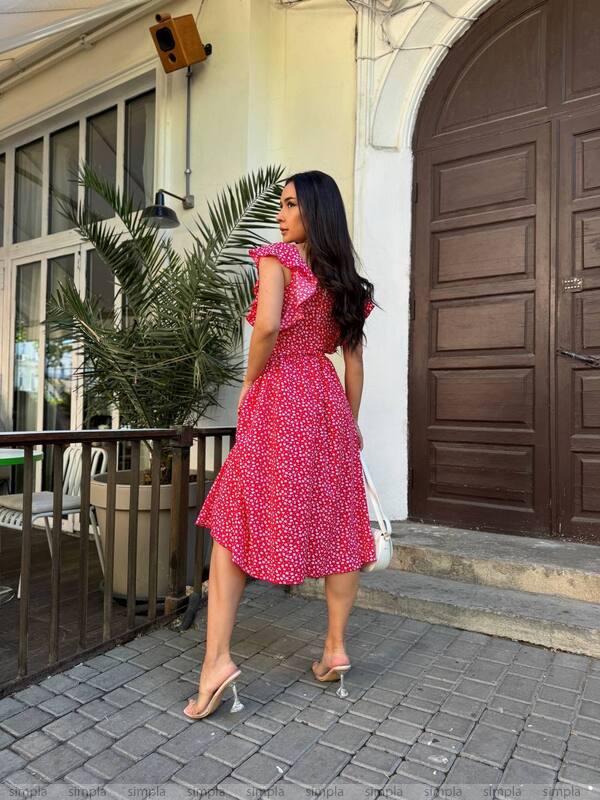 Woman in a pink dress standing on a sidewalk with a building in the background