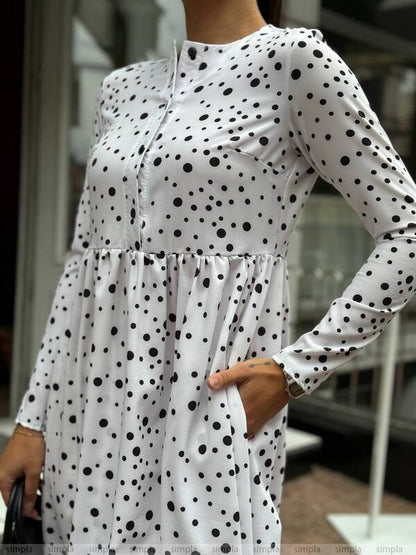 White dress with black polka dots worn by a person, blurred background