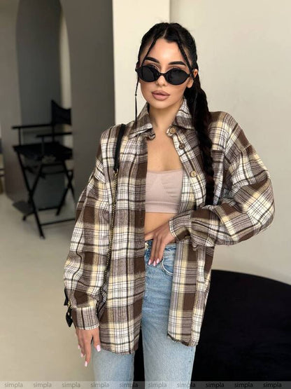 Person wearing a plaid shirt, beige top, and jeans indoors.