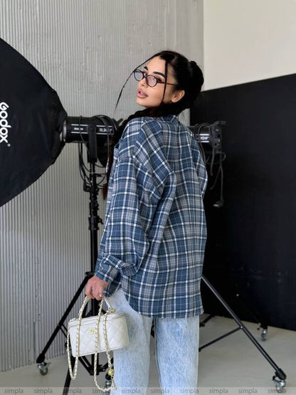 Person wearing a blue plaid shirt in a photography studio setting