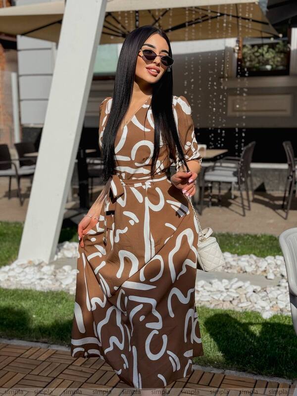 Woman wearing a brown and white patterned dress outdoors.
