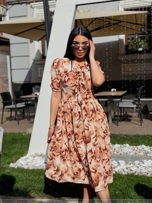Woman in a floral dress standing outdoors with a blurred background