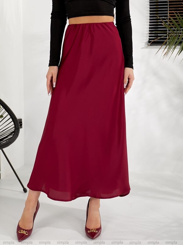 Person wearing a burgundy skirt with a black top on a white background