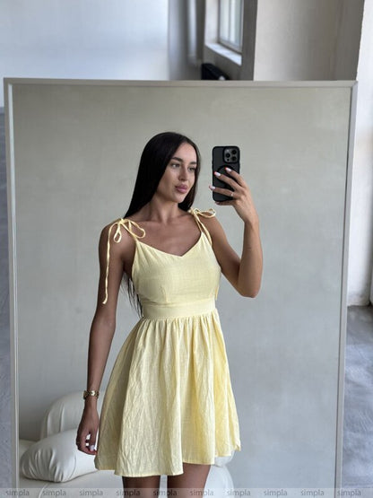 Woman taking a mirror selfie wearing a yellow dress.