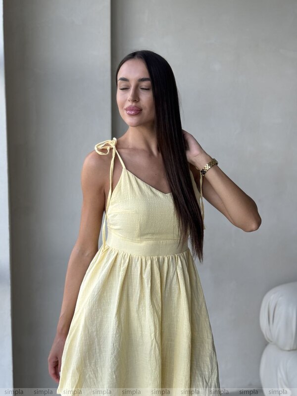 Woman wearing a light yellow dress against a neutral background