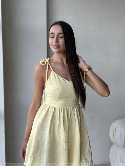 Woman wearing a light yellow dress against a neutral background
