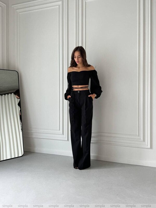Woman wearing a black outfit against a white wall