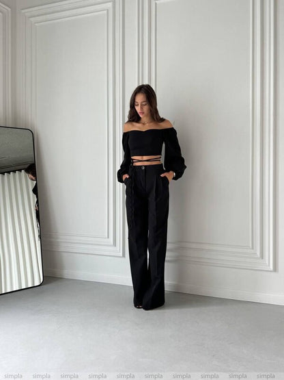 Woman wearing a black outfit against a white wall