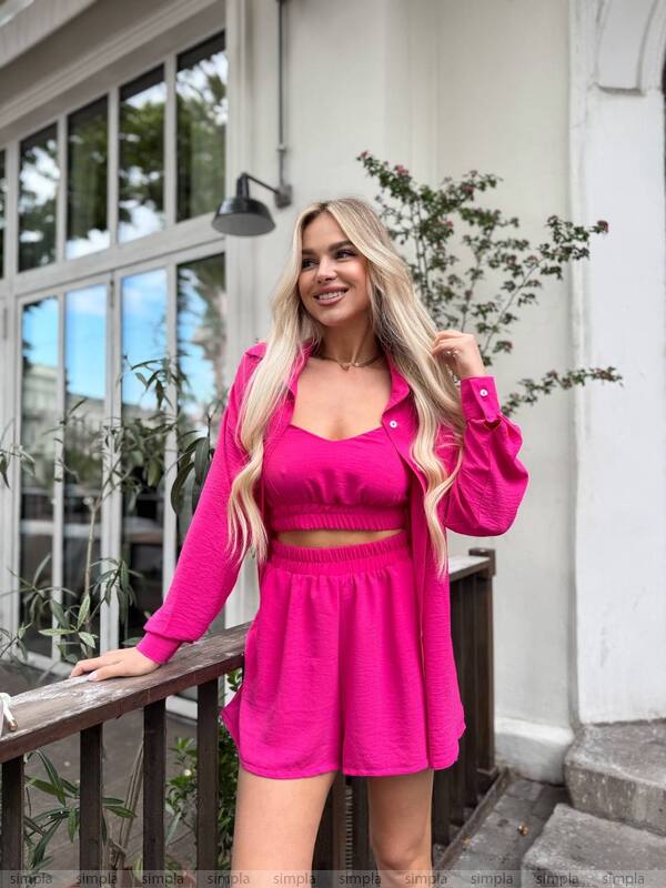 Woman in a bright pink outfit standing on a porch.