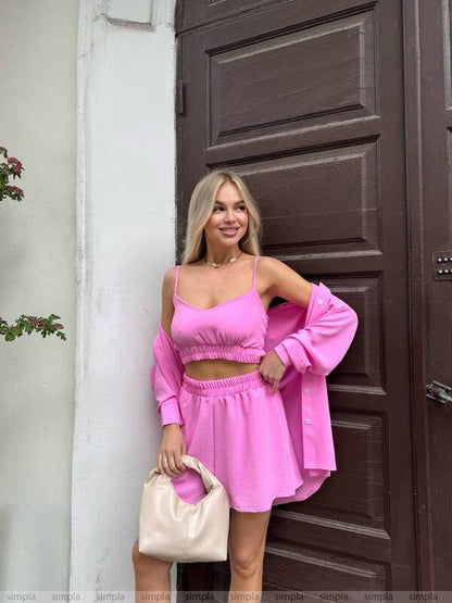Woman in a pink outfit standing in front of a brown door.