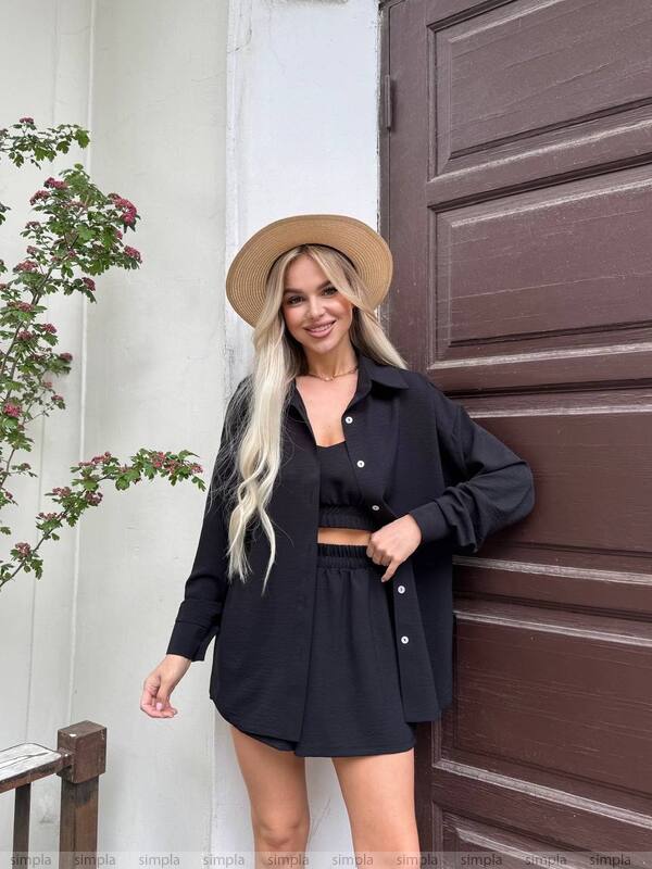 Woman in black outfit with beige hat standing next to a brown door