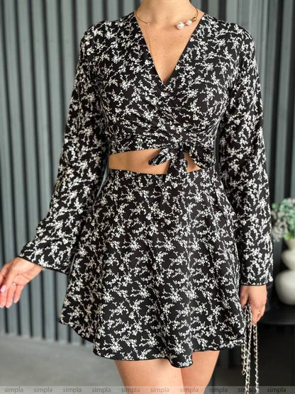 Black and white floral dress with long sleeves and a belt, worn by a person.