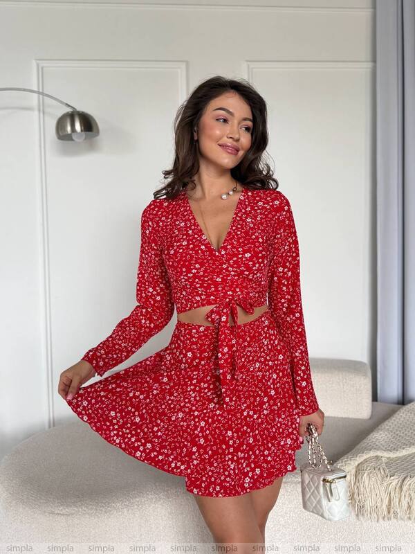 Woman wearing a red floral dress with long sleeves in a room.