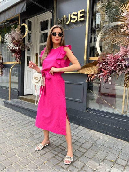 Woman in a pink dress standing in front of a building with 'MUSE' signage.