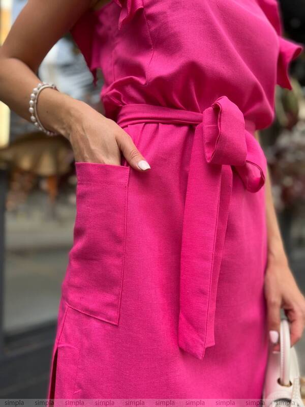 Close-up of a person wearing a bright pink dress with a belt, blurred background