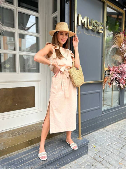 Woman in a beige dress and hat standing in front of a store named 'MUSE'.