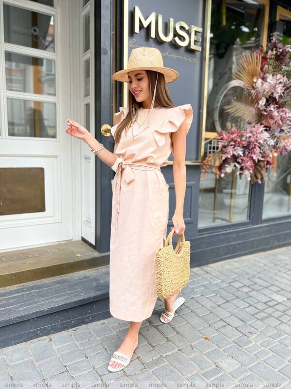 Woman in a pink dress and hat standing outside a store named 'MUSE'.
